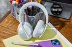 A pair of the best noise cancelling headphones leaned against a pencil holder on a desk with a Travel + Leisure Trusted badge.