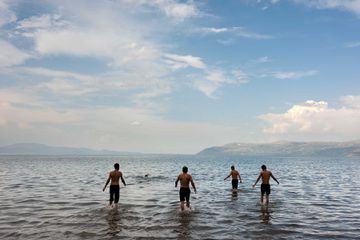 A group of four men wade into the water of a lake in Turkey