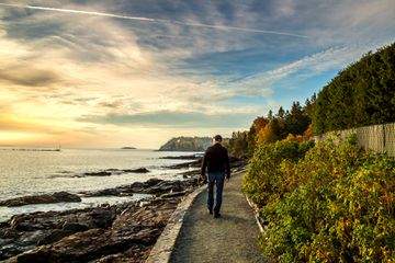 Man walking on Bar Harbor Maine Shore Path Trail at Sunrise during fall
