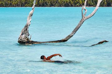 A swimmer in the water off of the Brando resort in French Polynesia
