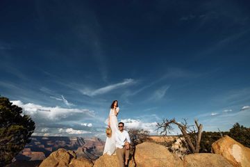 Newlyweds are sitting on a rock above Grand Canyon.