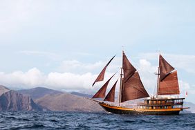The red-sailed Dunia Baru ship sailing in the waters off of Indonesia