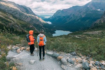 Two girls enjoying the beautiful view of the turquoise lake in the mountains in Glacier National Park, Montana