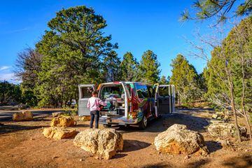 Young woman cooking at the gas stove of a camping van, campervan, camping, RV, Mather Campground, Grand Canyon National Park, South Rim, near Tusayan, Arizona