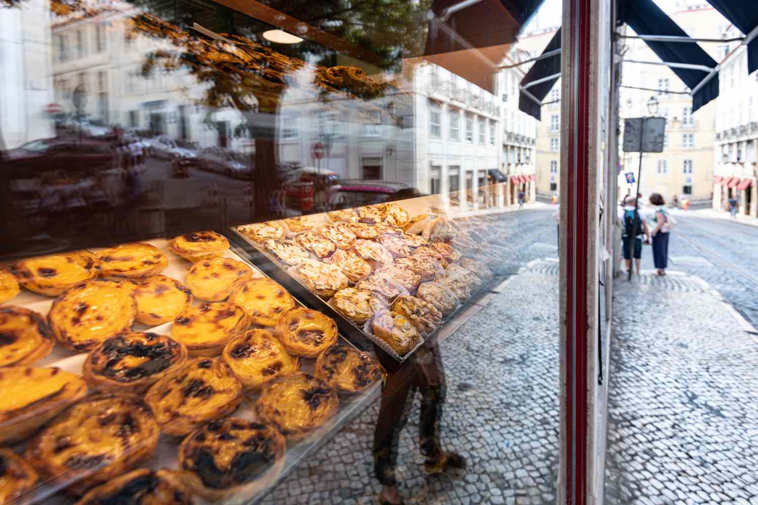 portuguese pastries in lisbon behind bakery window with reflection of the city