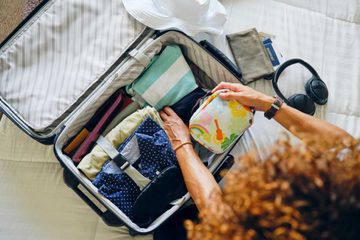A woman in a home, packing a suitcase to go on a vacation.