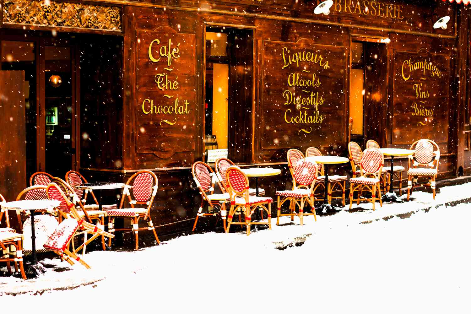 Parisian cafe with sidewalk tables in winter with the snow falling