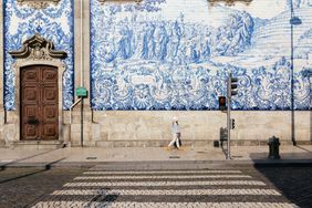 Tourist girl walking through the streets in Porto, against the azulejos wall of Igreja do Carmo church in background. Portugal, Europe