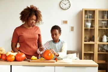 Mother Watching Son Carving Pumpkin