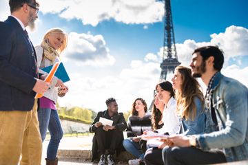 A group of people reading and talking together in front of the Eiffel Tower