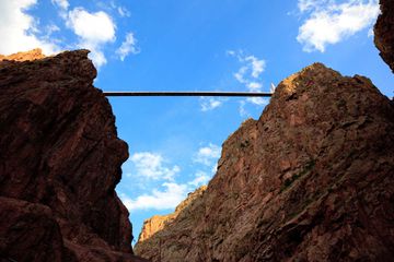 looking up at a rigid straight bridge hangs between two mountains