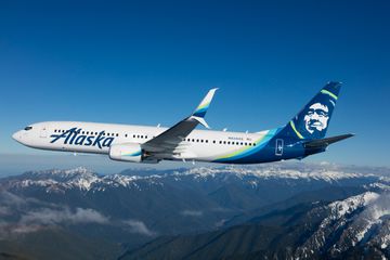 Alaska Air plane in the air over snow capped mountains