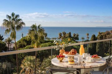 Breakfast on the presidential balcony and views of palm trees and the ocean at Anatara Plaza Nice Hotel