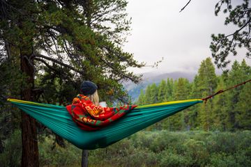 View of woman relaxing in a hammock in San Isabel National Forest in the Angel of Shavano campground