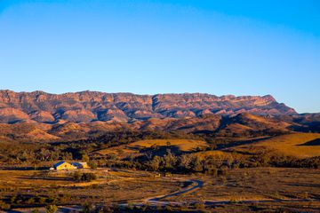 A yellow hued building with a view of Australia's mountainous Flinders Range during sunset