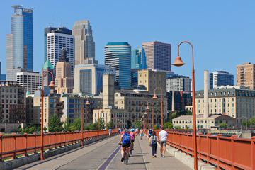 The Minneapolis skyline and people biking over the Stone Arch Bridge