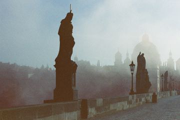 statues on a bridge on a foggy day 