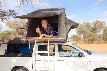 Women in car roof tent on top of a trunk