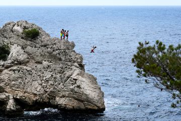 Young men cliff jump into the sea in the Parc National des Calanques in Marseille, southern France