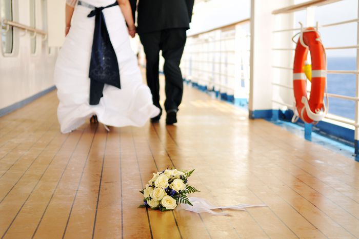 Wedding couple walking in the distance with bouquet in front on a deck of a cruise ship