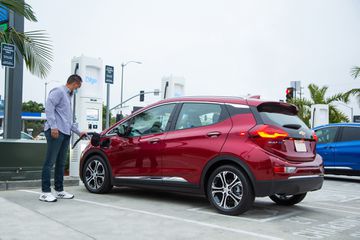 A man charges a electric vehicle at a charging station