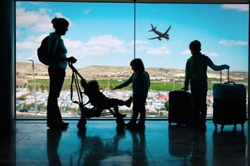 A mom and three kids seen in silhouette in front of an airport window