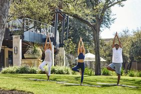 Three adults in tree pose during outdoor yoga at Four Seasons Austin