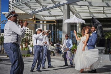 A bride and groom walk with a jazz band at the Four Seasons Hotel New Orleans