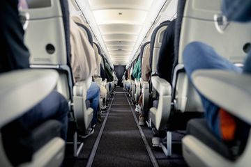 Interior of commercial aircraft cabin with rows of seats down the aisle