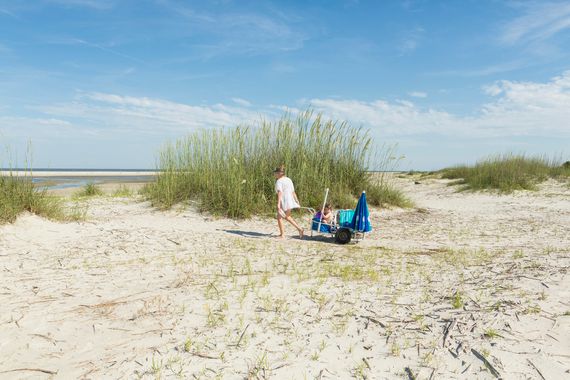 Caucasian mother pulling son in cart on the beach on the Golden Isles