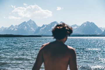 The back of a person in front of a large lake and mountains