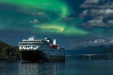 A Havila Kystruten ship sailing under the Norther Lights