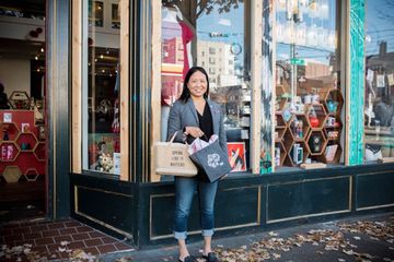 A woman standing outside of a store with shopping bags 