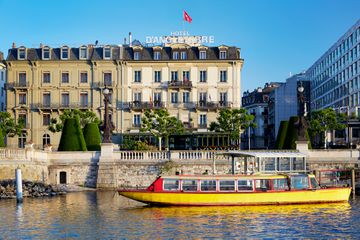 Exterior of hotel on a river with a boat passing by