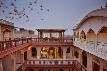 Birds fly over a hotel in a restored mansion in India