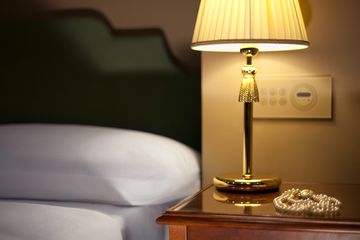 A necklace on a nightstand in a hotel room 