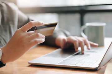 A woman holding a credit card while on her laptop 