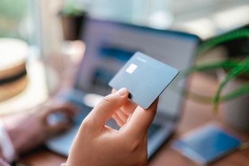 Woman paying for tickets on vacation with credit card and laptop