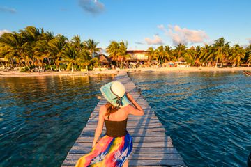 Woman walking on a pier to a tropical island