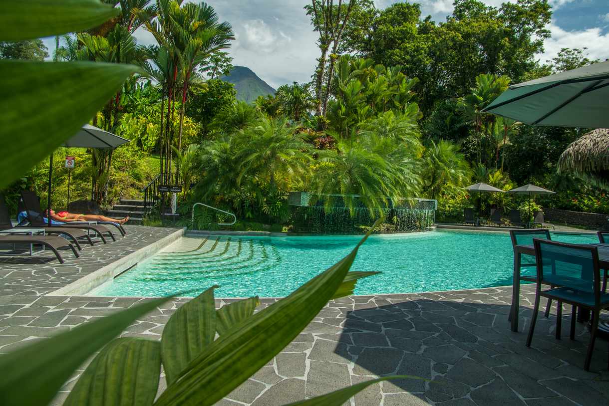 Arenal peaking over green plants at Tabacon Hot Springs
