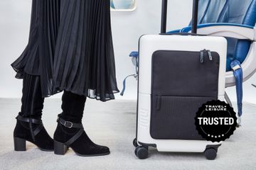 Passenger rolling July Carry On Pro SnapSleeve near airplane seats