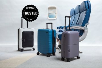 Three pieces of luggage near airplane seats and window