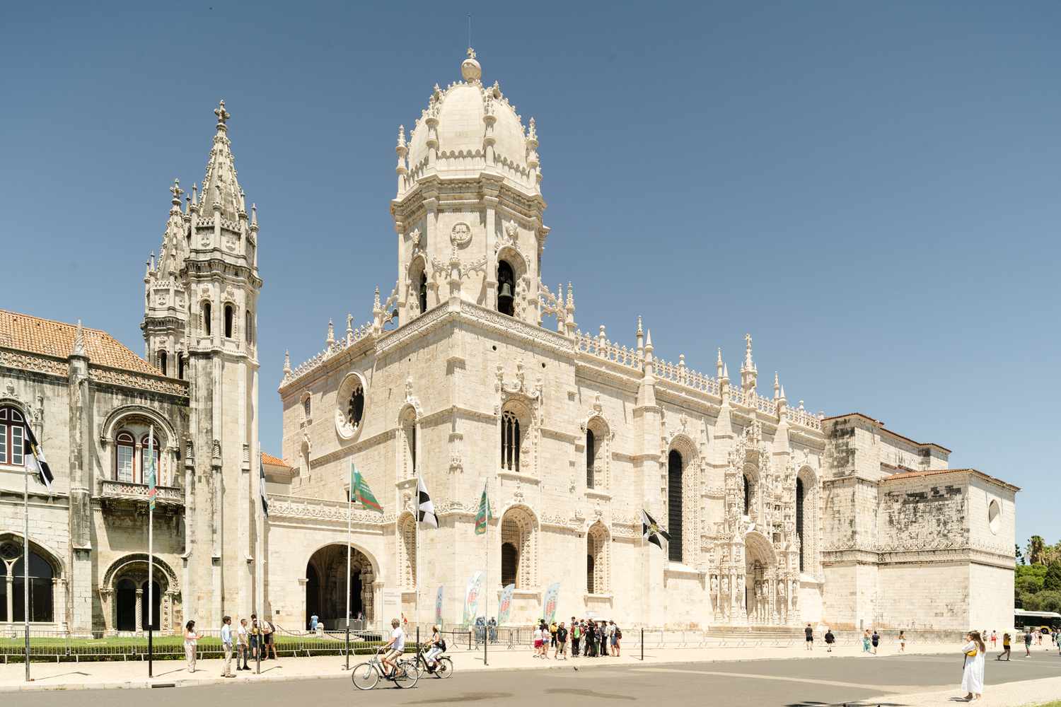 People biking past Mosteiro dos Jeronimos