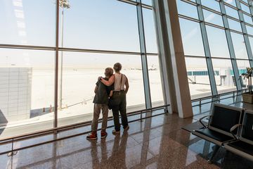 An airport waiting room where mother and son are standing by the airport window