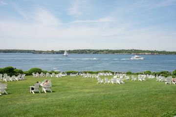 White chairs on a lawn overlooking the bay with sailboats