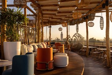 Rooftop terrace with lounge seating and view of the city and palm trees at Nobu Hotel Marrakech