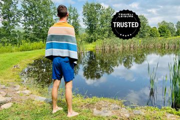 The Nomadix Original Towel draped over the shoulders of a person next to a pond