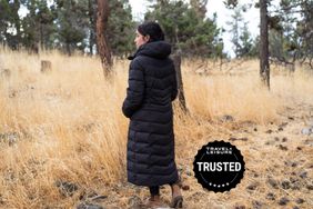 A woman wears an Ororo Soho Women's Heated Parka outdoors