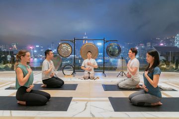 A group of hotel guests are being guided in a gong bath session on the Peninsula Hong Kong rooftop