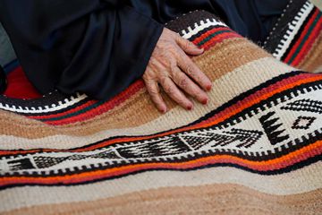 A woman's hand on a colorful woven textile